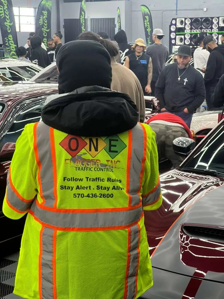 Crew member wearing a One Flagger Inc safety vest with company slogan